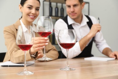Sommeliers tasting different sorts of wine at table indoors