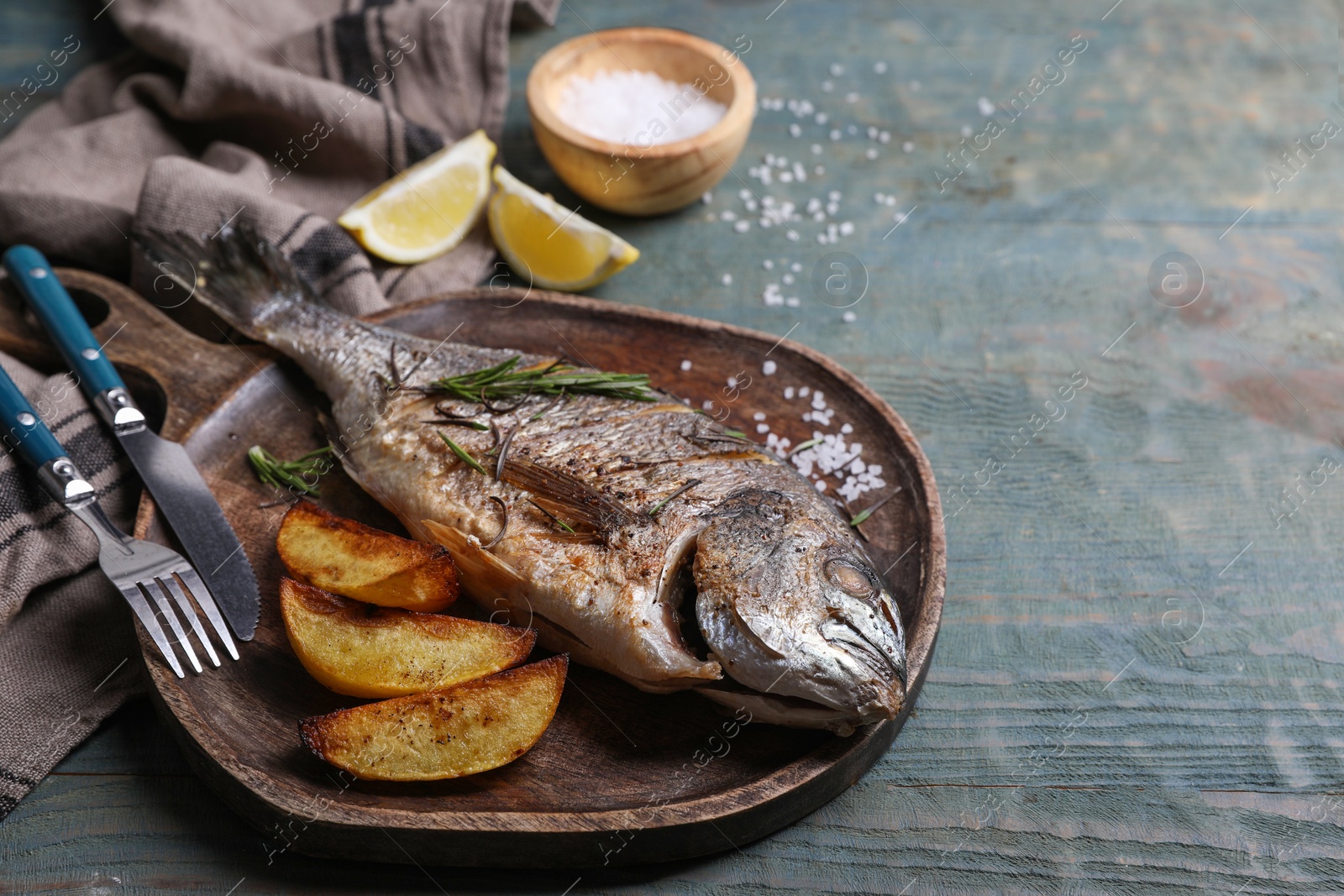 Photo of Seafood. Delicious baked fish served on wooden rustic table, space for text