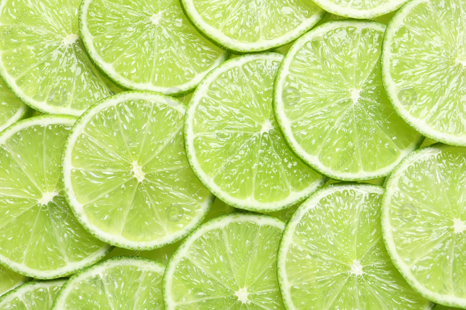 Photo of Fresh sliced ripe limes as background, top view