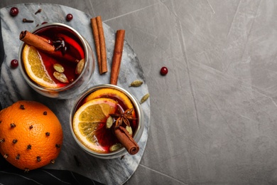 Board with glasses of tasty mulled wine on grey table, flat lay. Space for text