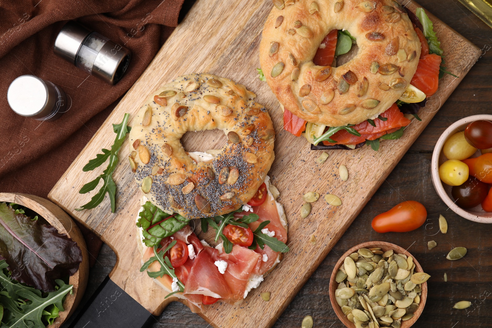 Photo of Tasty bagel sandwiches on wooden table, flat lay