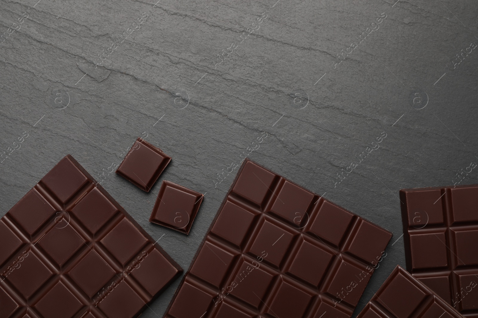 Photo of Delicious dark chocolate on black table, flat lay. Space for text