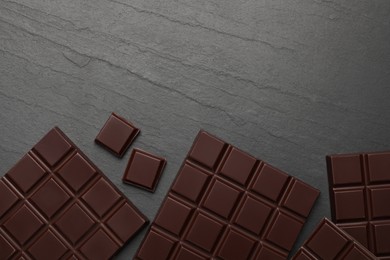 Photo of Delicious dark chocolate on black table, flat lay. Space for text
