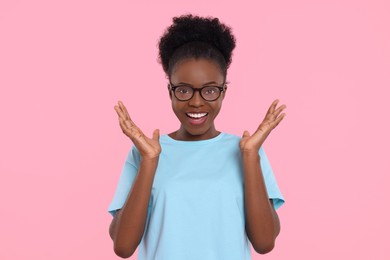 Photo of Portrait of happy young woman in eyeglasses on pink background