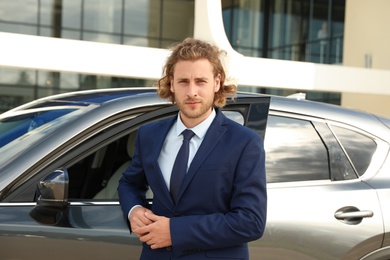 Photo of Attractive young man near luxury car outdoors