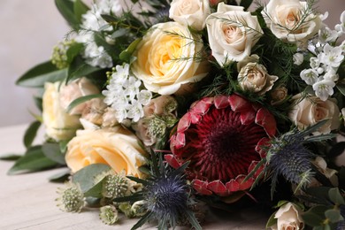 Photo of Beautiful bouquet with roses on white wooden table, closeup