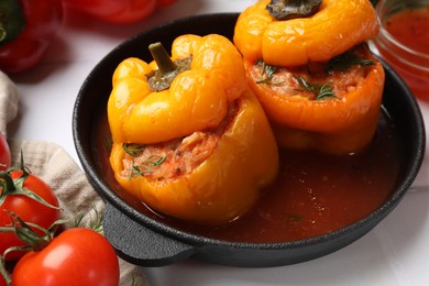 Photo of Tasty stuffed peppers and tomato on light table, closeup