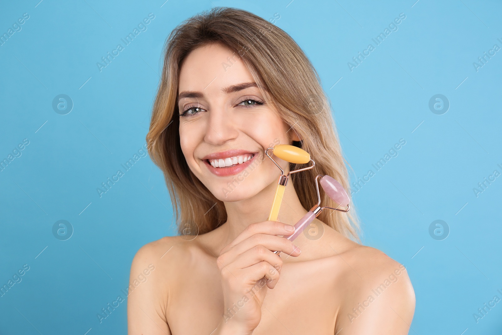 Photo of Young woman with natural face rollers on light blue background