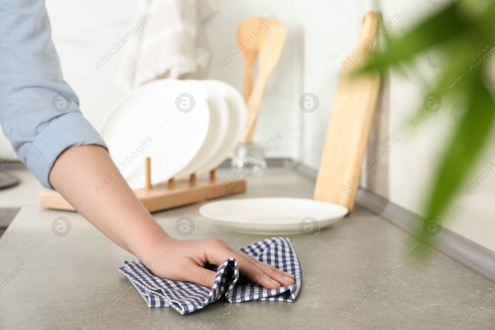 Photo of Woman wiping kitchen countertop with towel, closeup