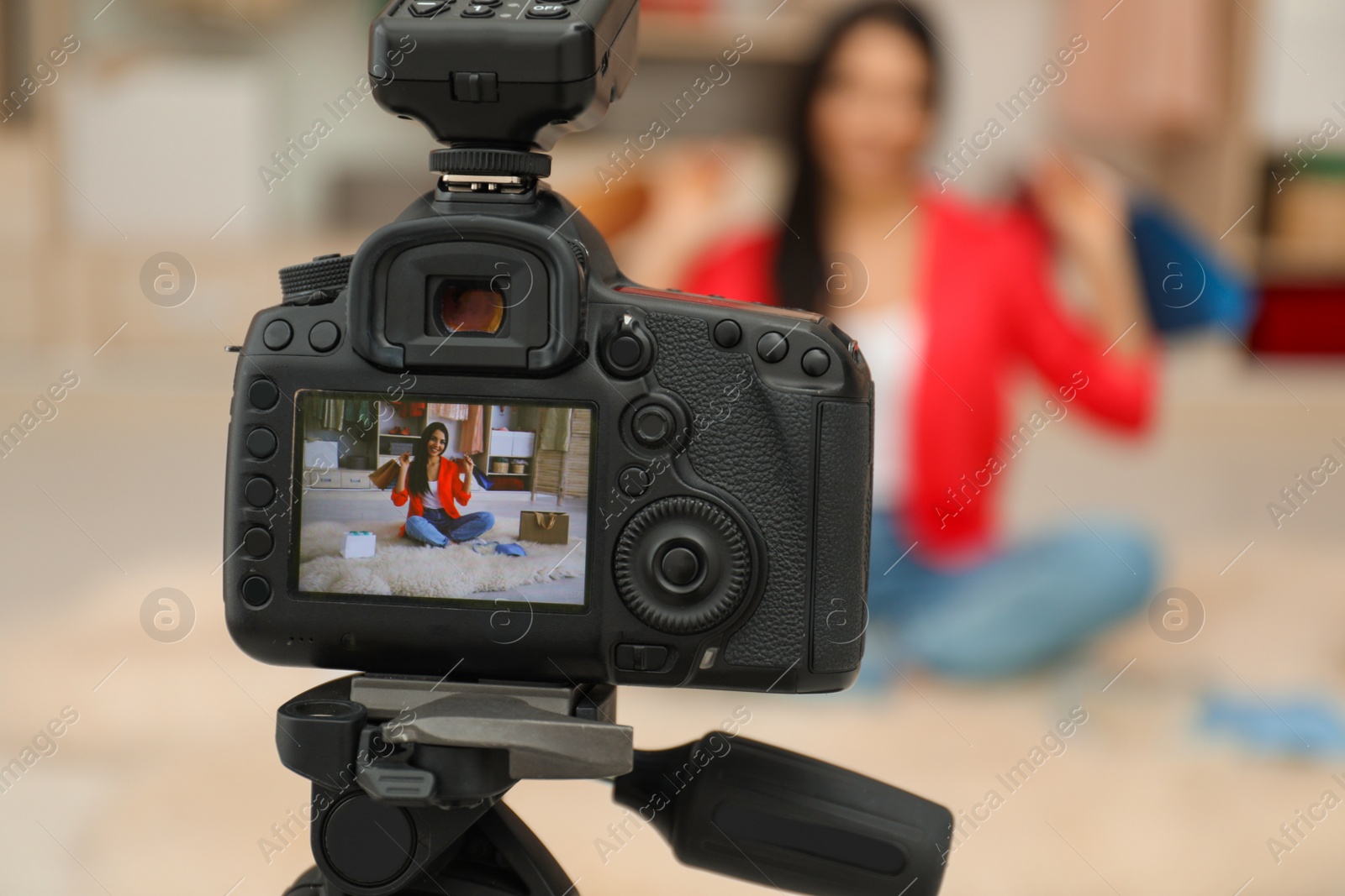 Photo of Fashion blogger recording new video in room, focus on camera