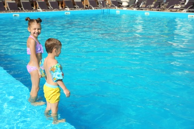 Little children standing in swimming pool on sunny day