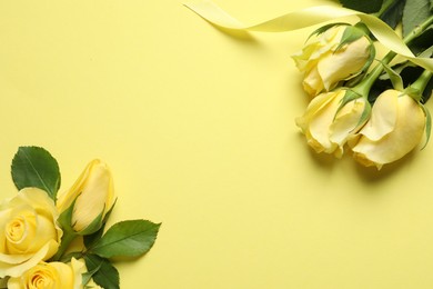 Beautiful yellow roses and ribbon on color background, flat lay. Space for text