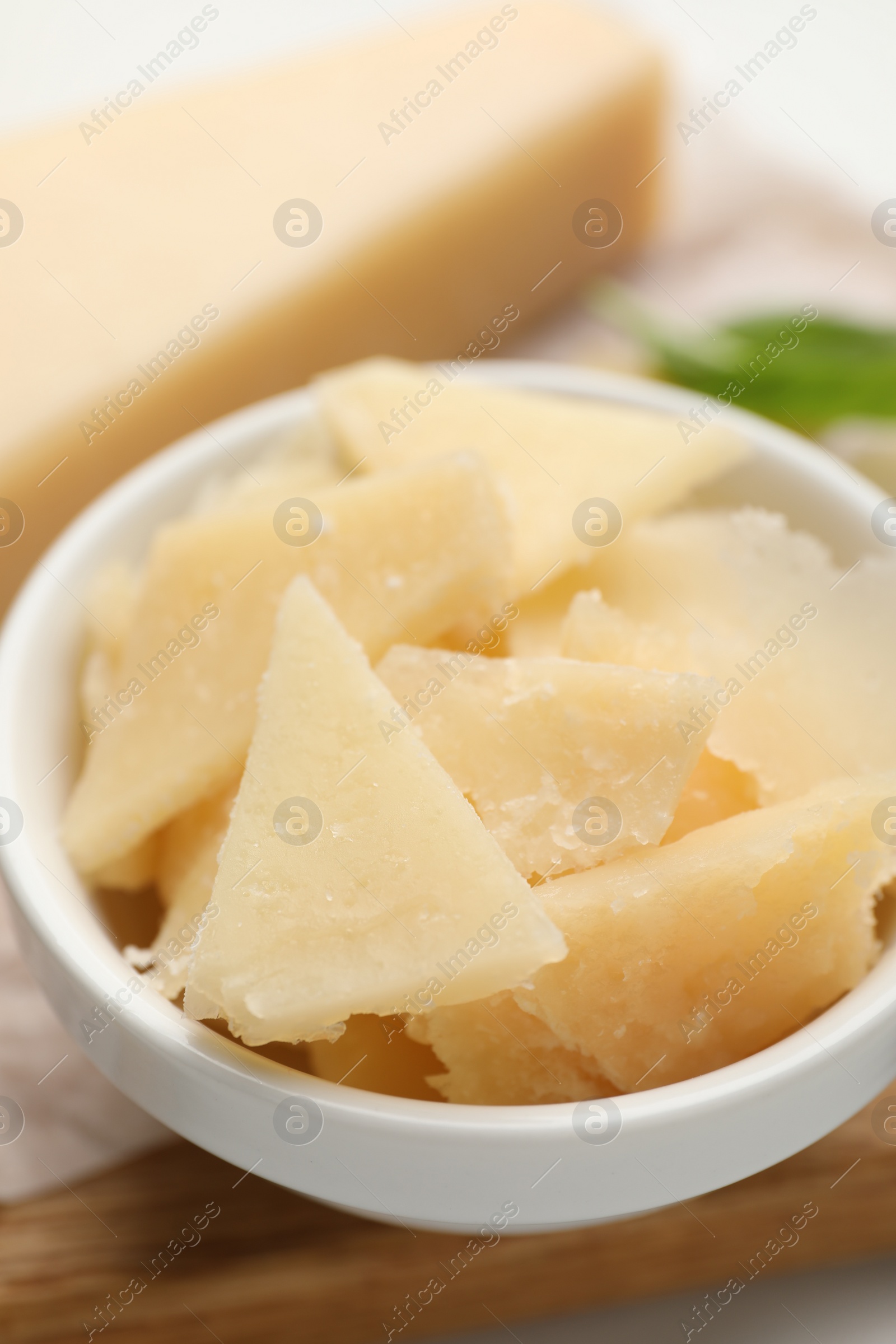 Photo of Bowl with parmesan cheese pieces on table, closeup