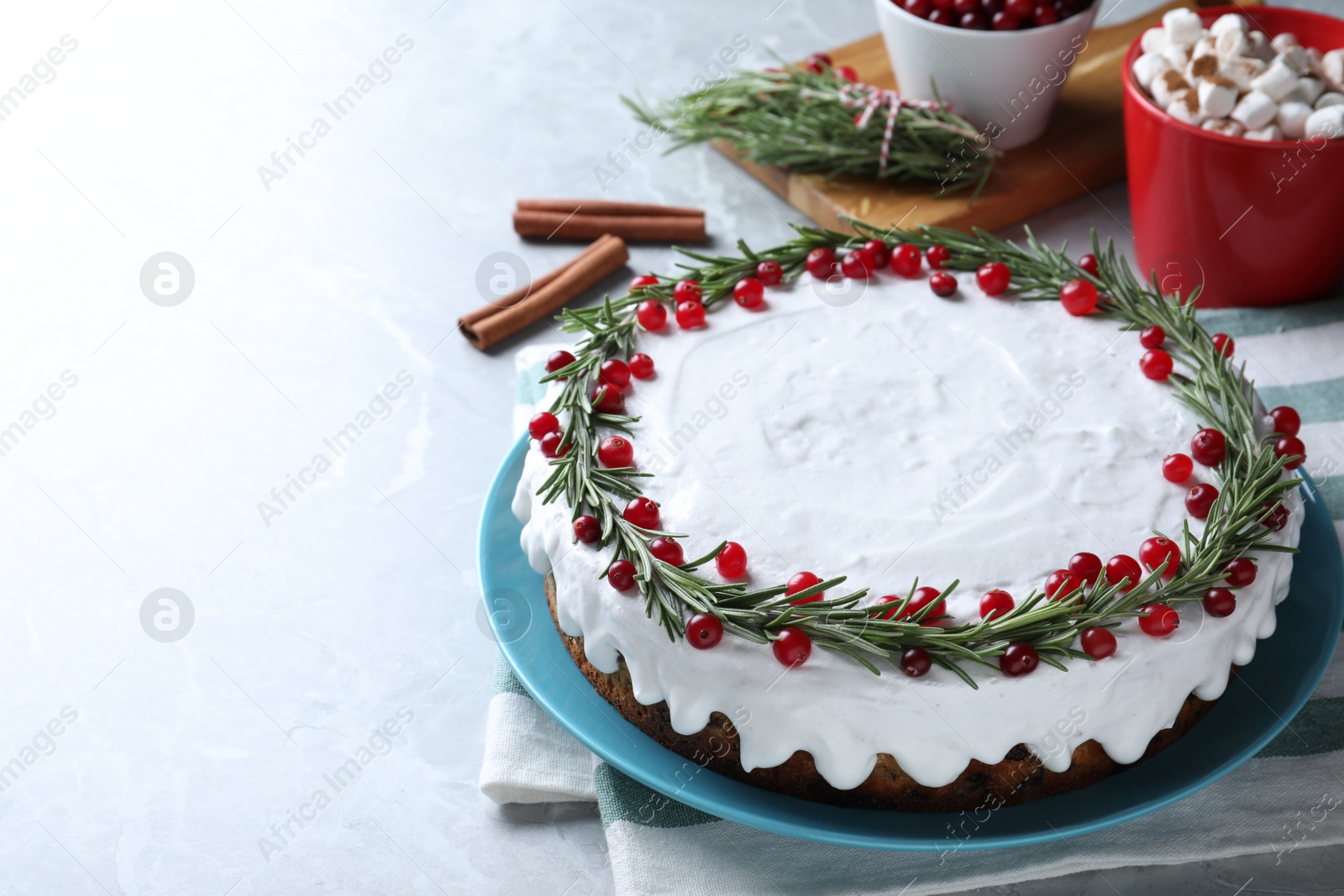 Photo of Traditional Christmas cake decorated with rosemary and cranberries on light grey marble table, space for text