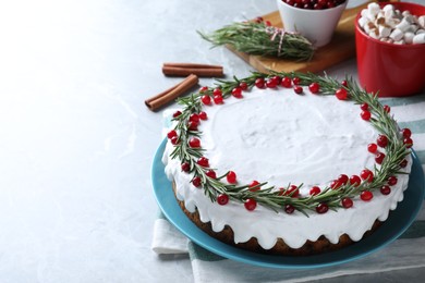 Traditional Christmas cake decorated with rosemary and cranberries on light grey marble table, space for text