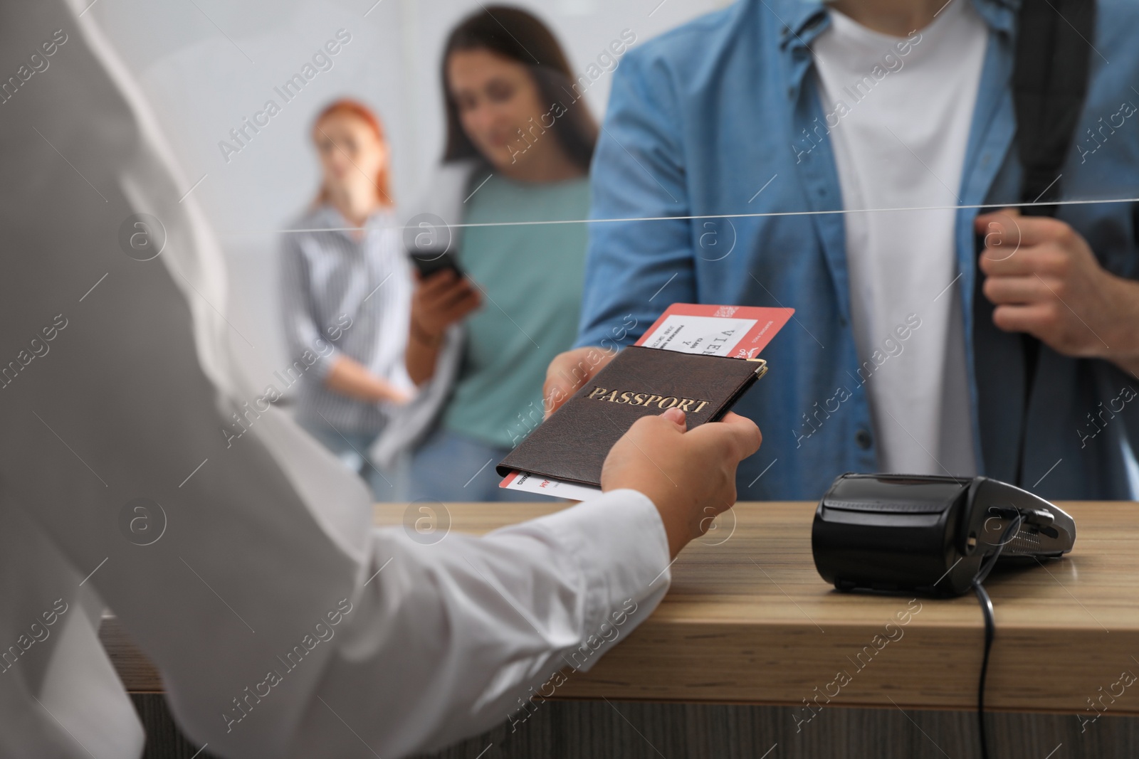 Photo of Agent giving passport with ticket to client at check-in desk in airport, closeup