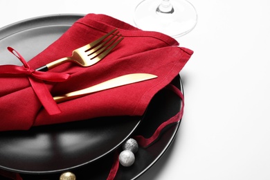 Beautiful table setting with golden cutlery and red napkin on white background, closeup