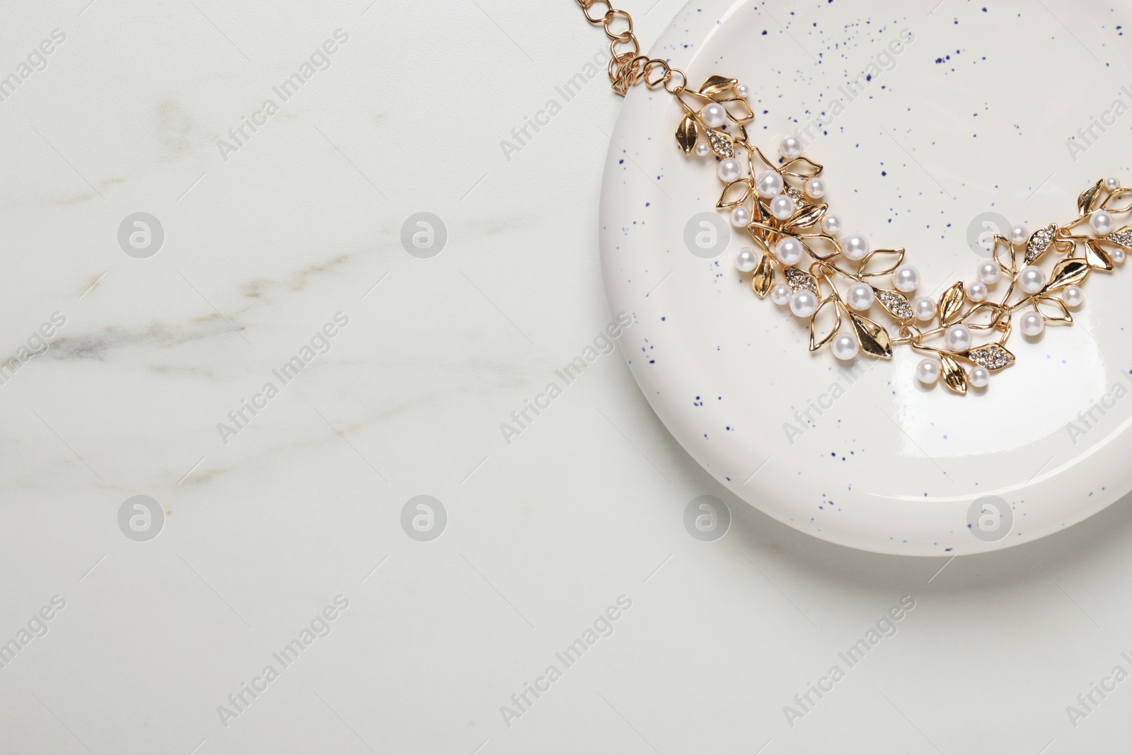 Photo of Beautiful necklace on white marble table, top view with space for text. Luxury jewelry