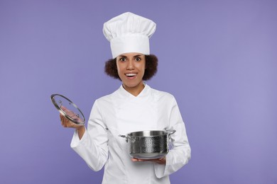 Photo of Happy female chef in uniform holding cooking pot on purple background