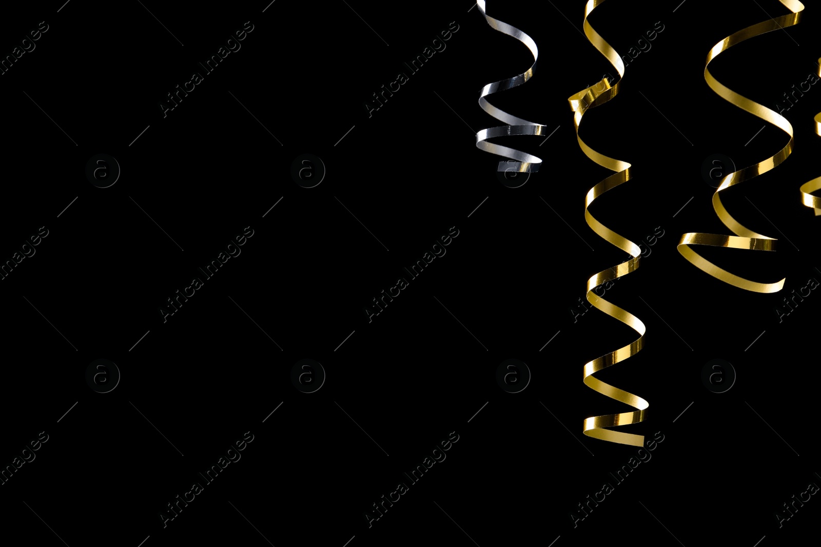 Photo of Shiny serpentine streamers on black background. Space for text