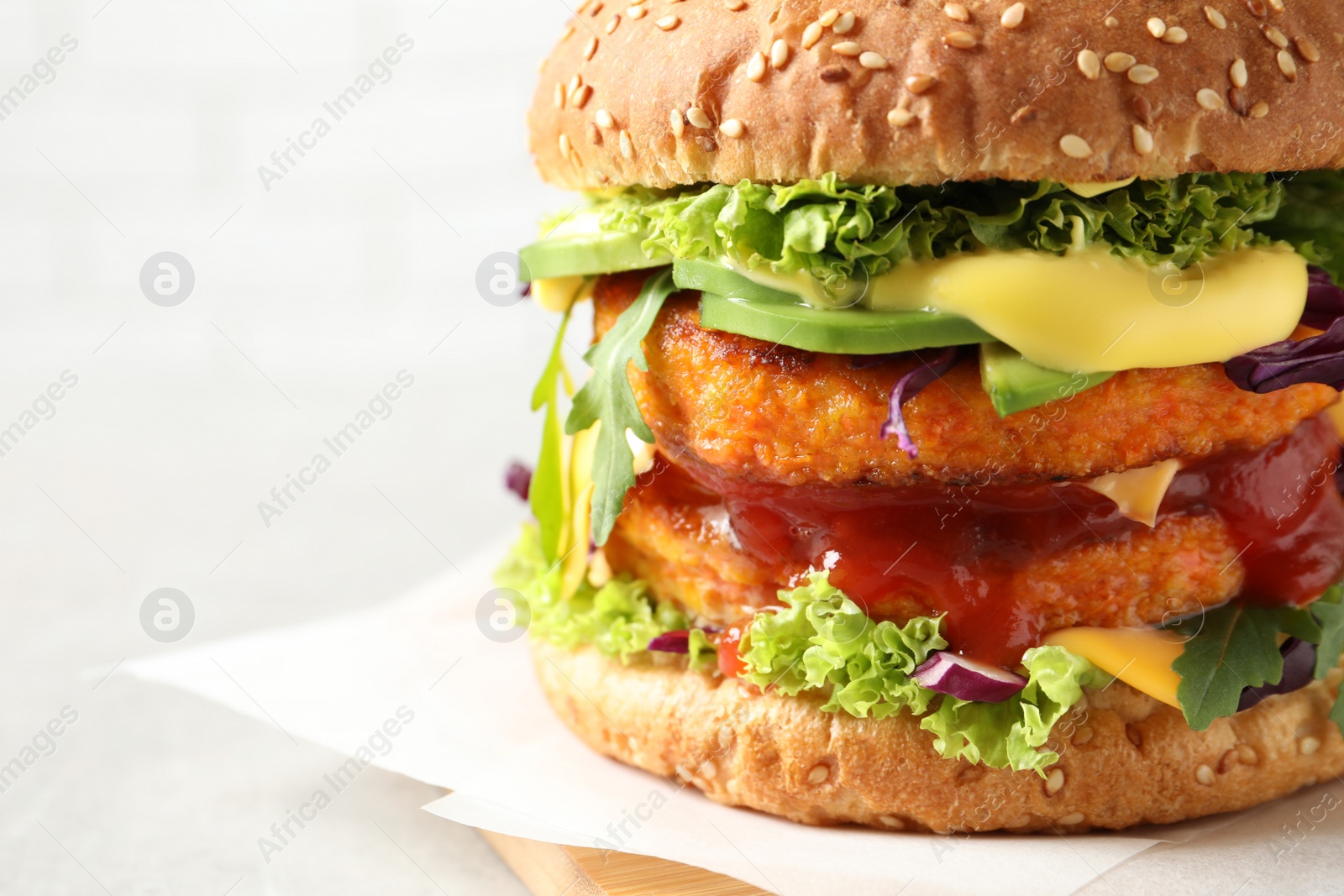 Photo of Vegan burger with carrot patties on light background, closeup. Space for text