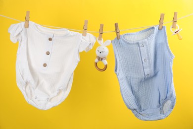 Photo of Baby clothes and accessories hanging on washing line against yellow background