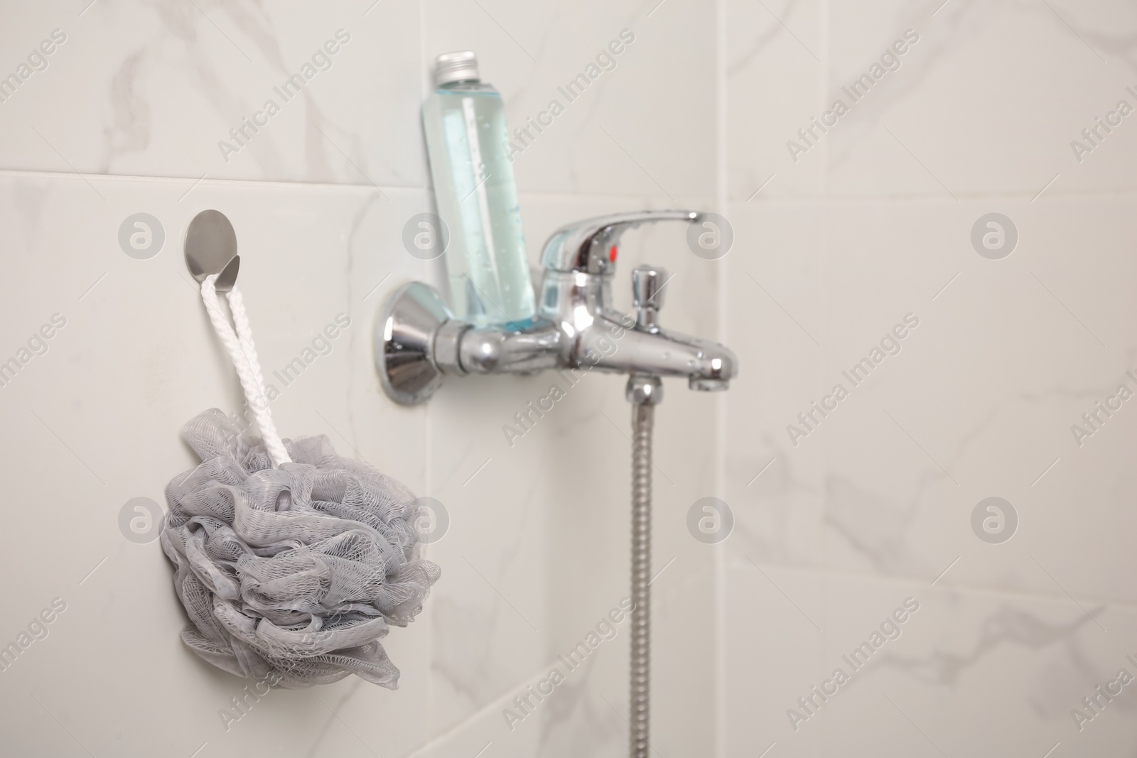 Photo of Grey shower puff and bottle of body wash gel in bathroom, space for text