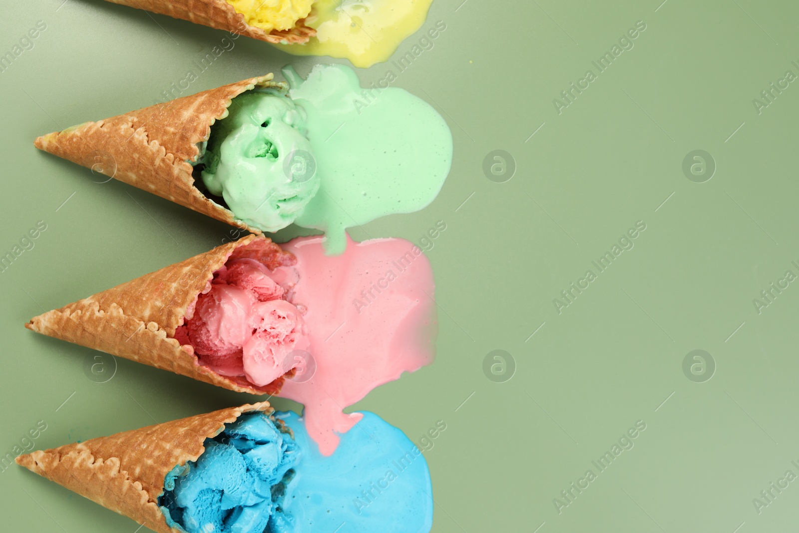 Photo of Melted ice cream in wafer cones on pale green background, flat lay. Space for text