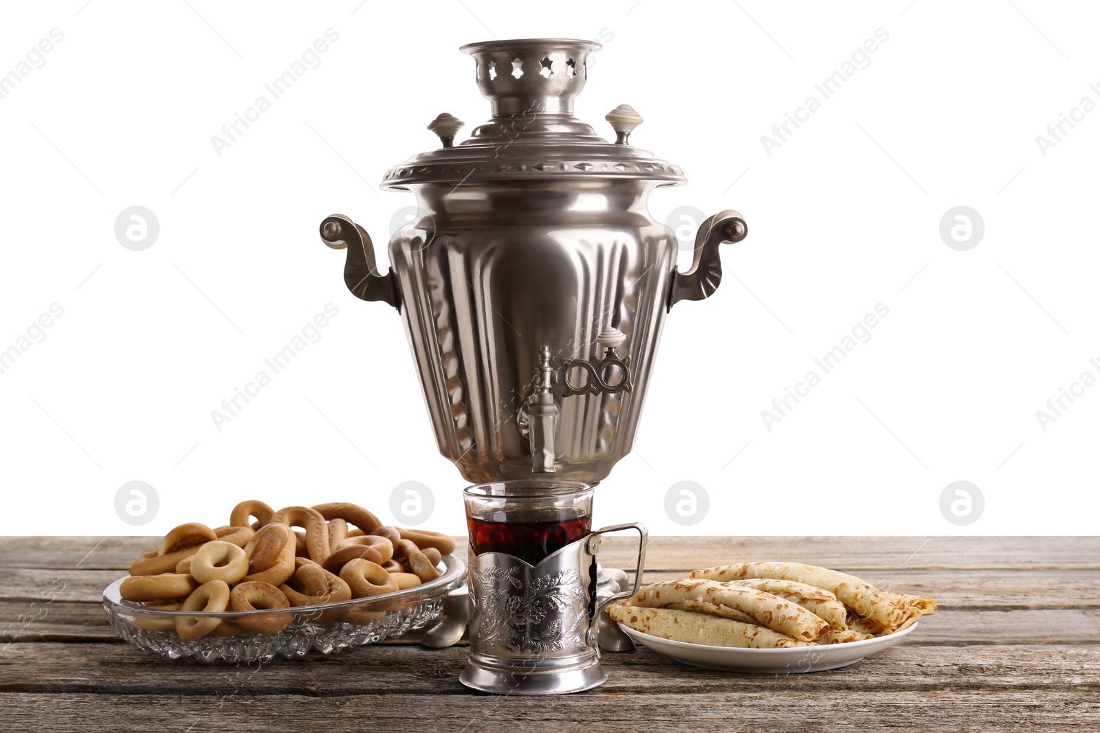 Photo of Vintage samovar, cup of hot drink and snacks on wooden table against white background. Traditional Russian tea ceremony