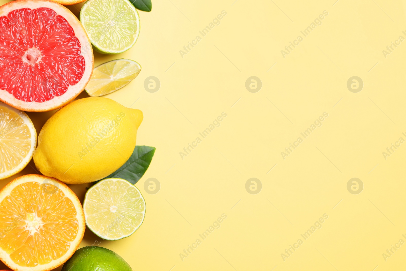 Different cut and whole citrus fruits on yellow table, flat lay. Space for text Photo of Different cut and whole citrus fruits on yellow table, flat lay. Space for text