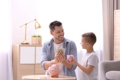 Family with piggy banks and money at home