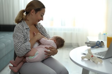 Photo of Young woman breastfeeding her baby at home