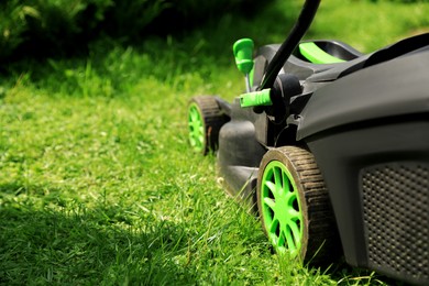 Lawn mower on green grass in garden. Space for text