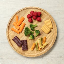 Board with different finger foods for baby on wooden table, top view