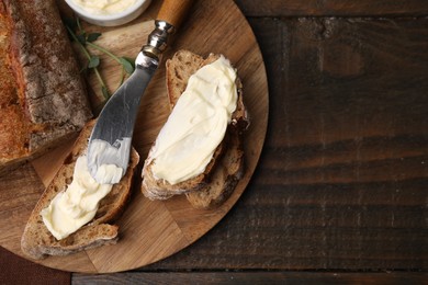 Photo of Tasty bread with butter and knife on wooden table, top view. Space for text