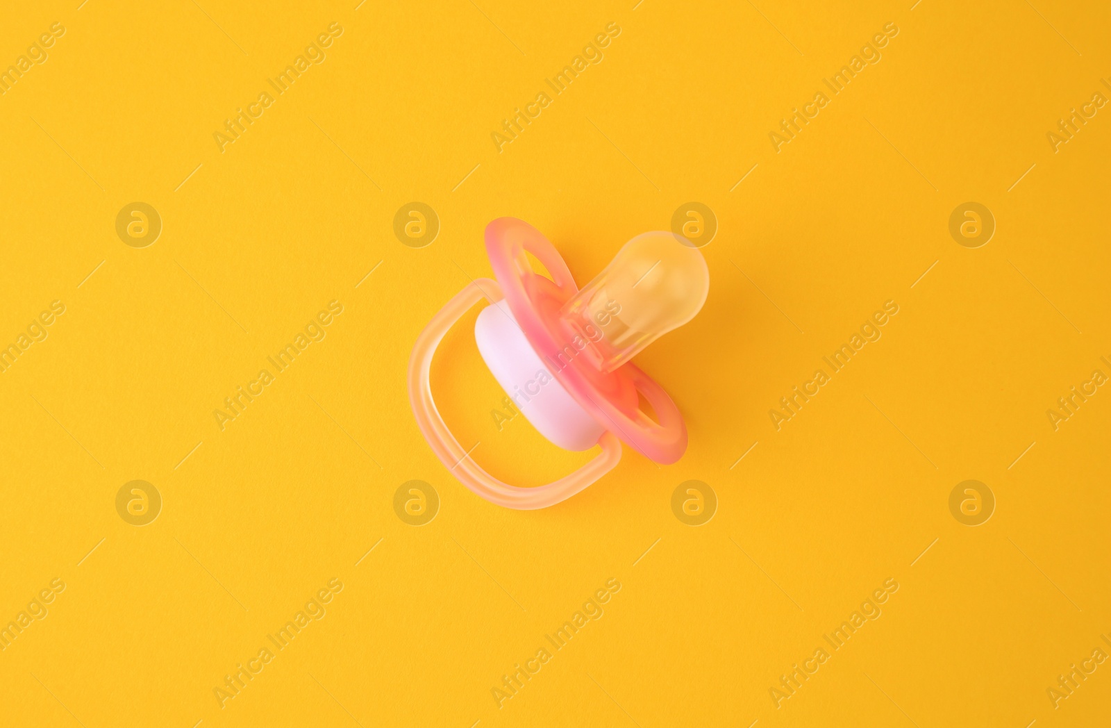 Photo of One new baby pacifier on orange background, top view