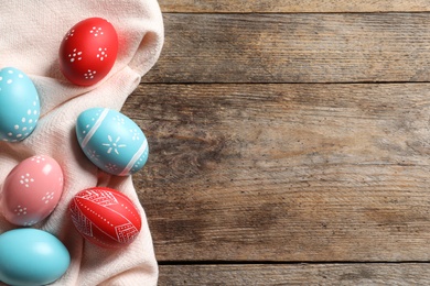 Flat lay composition of colorful painted Easter eggs on wooden table, space for text