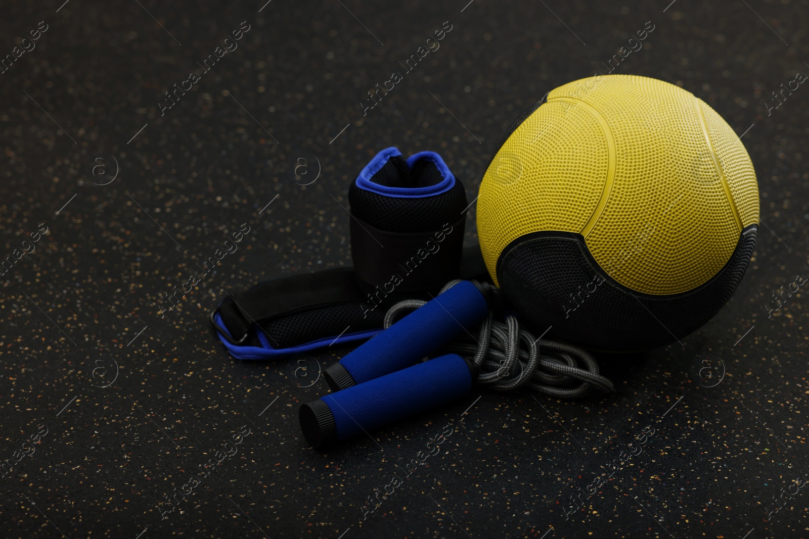 Photo of Yellow medicine ball, weighting agents and skipping rope on floor, space for text