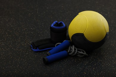 Photo of Yellow medicine ball, weighting agents and skipping rope on floor, space for text
