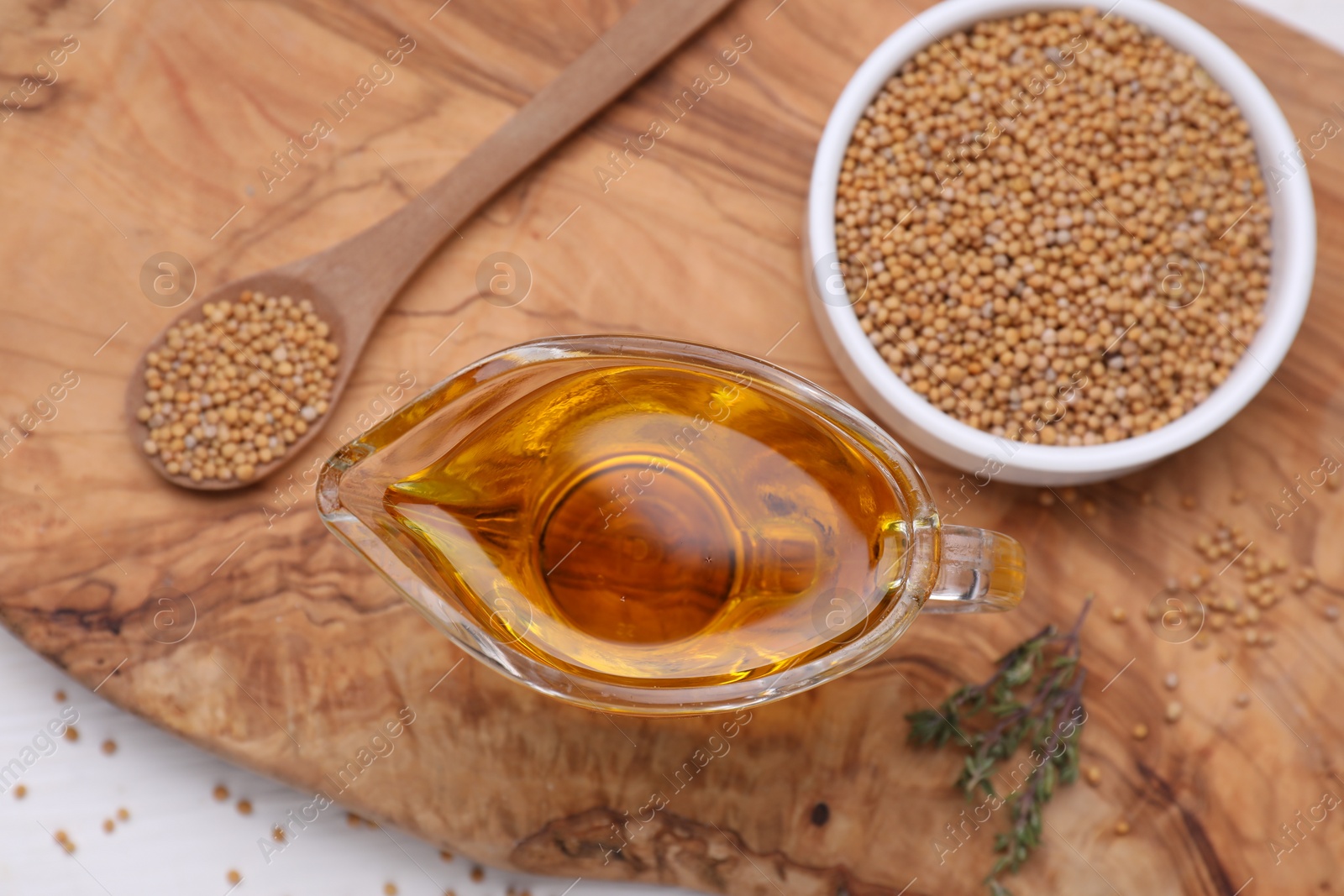 Jug of natural oil and mustard seeds on wooden table, flat lay Photo of Jug of natural oil and mustard seeds on wooden table, flat lay