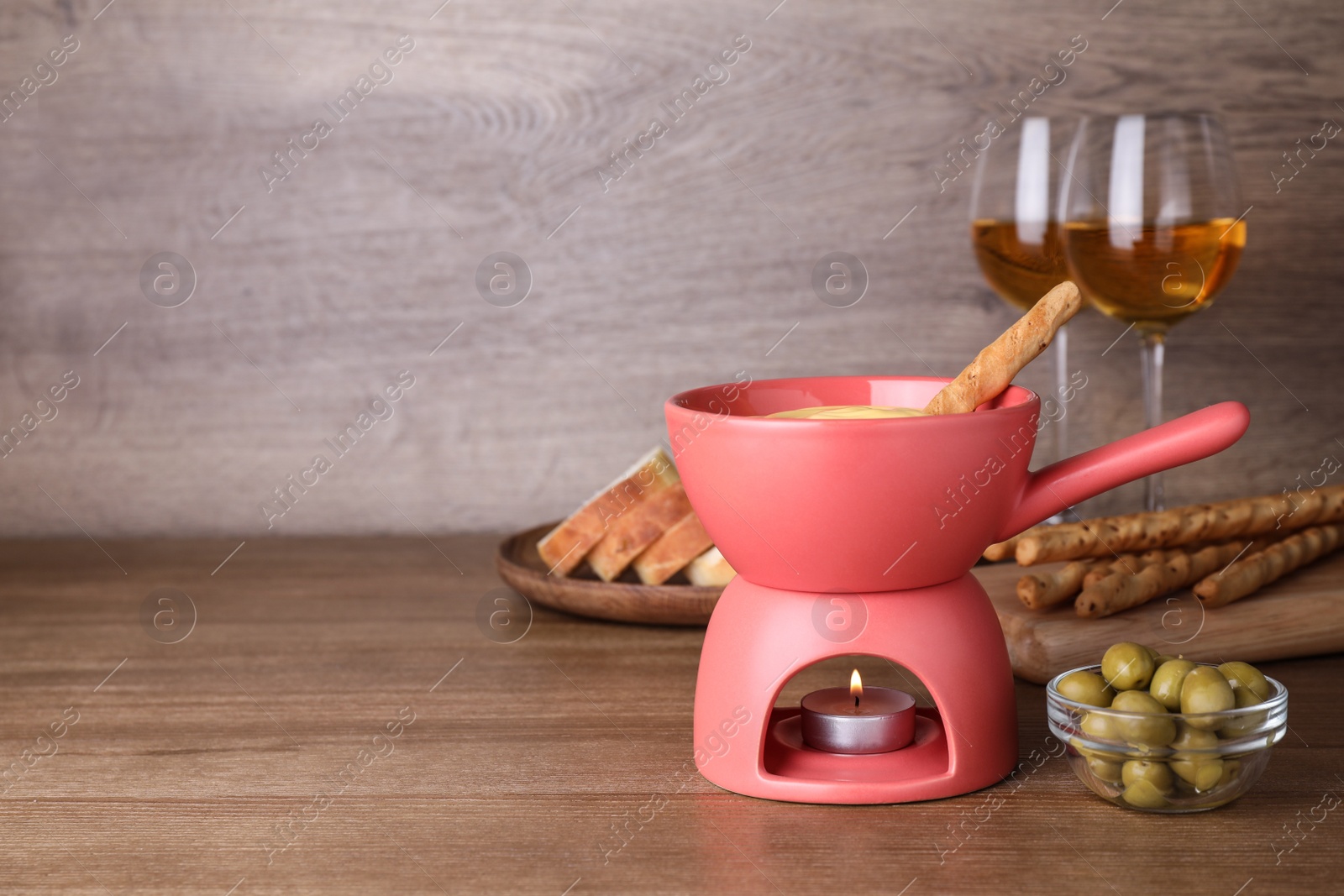 Photo of Composition with pot of tasty cheese fondue on wooden table, space for text