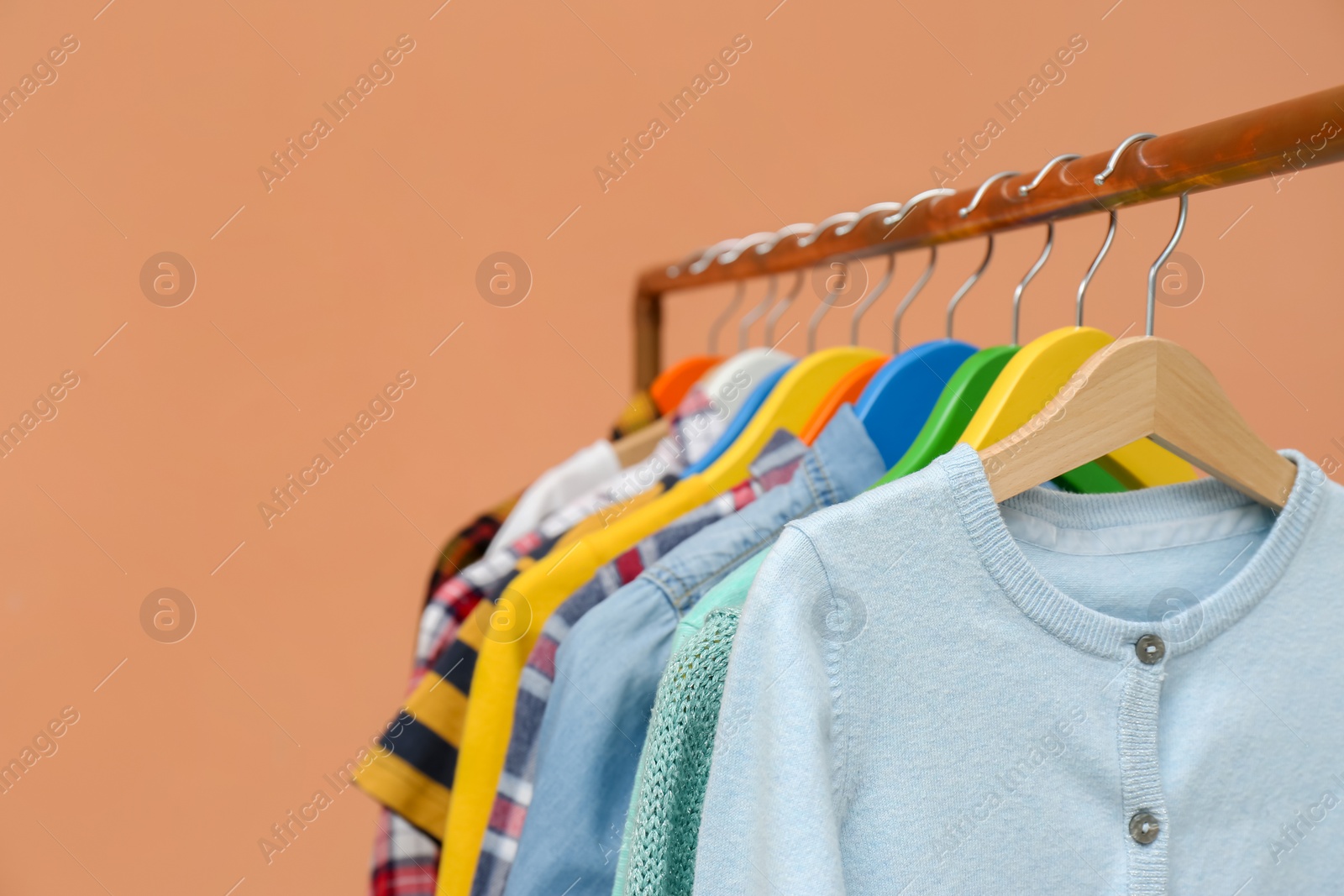 Photo of Rack with stylish children clothes on beige background, closeup. Space for text