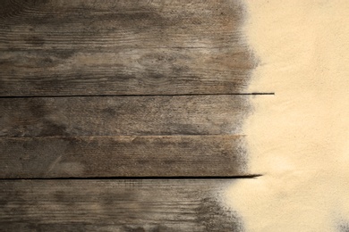 Photo of Beach sand on wooden background, top view with space for text