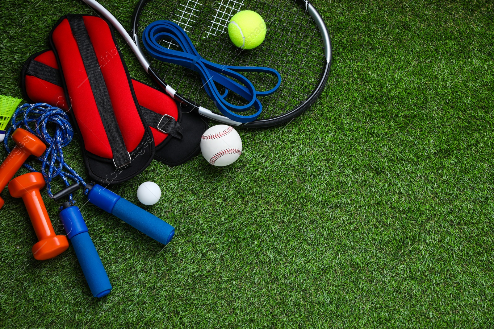 Photo of Set of different colorful sports equipment on green grass, flat lay. Space for text