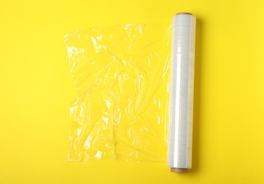 Photo of Roll of plastic stretch wrap film on yellow background, top view