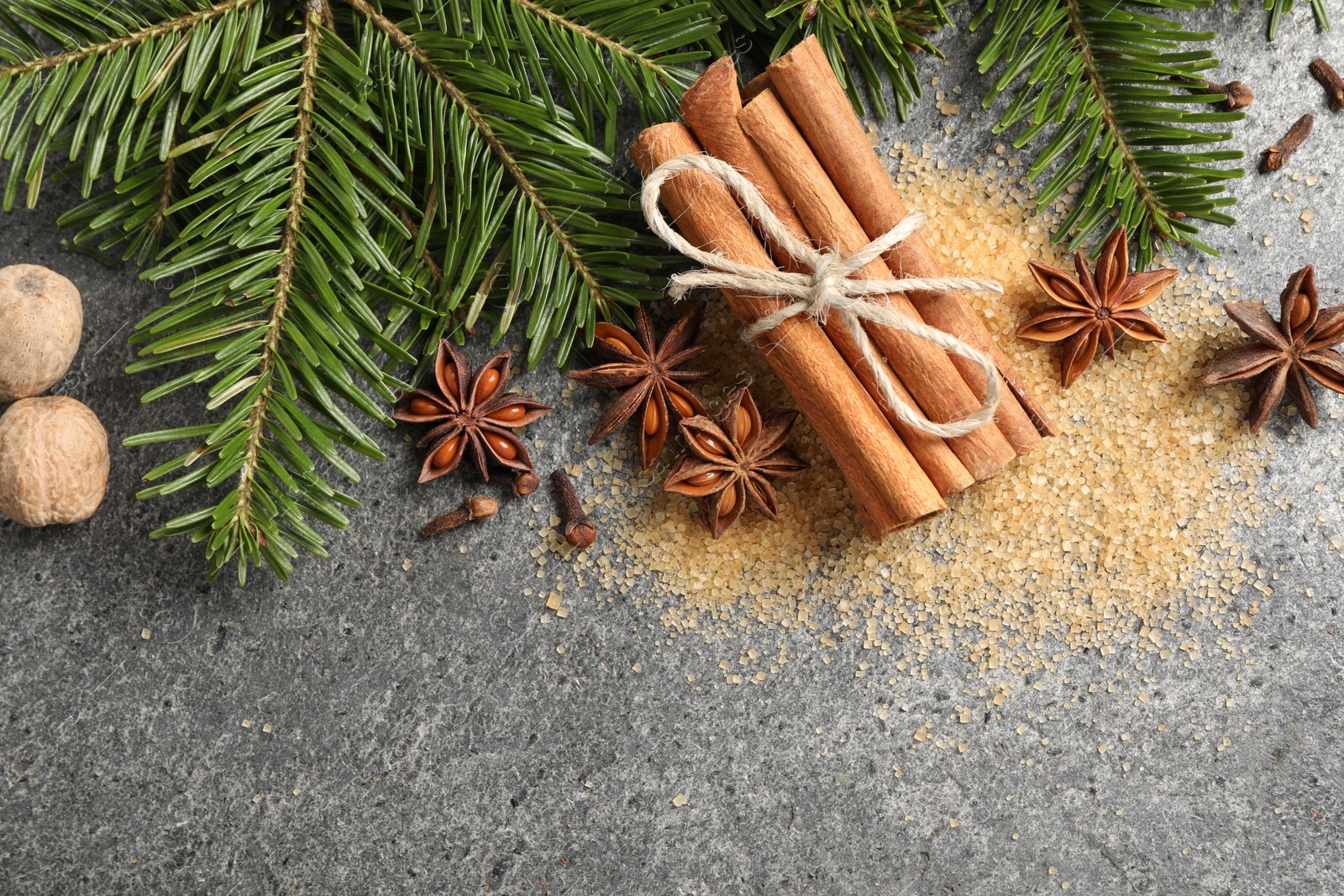 Photo of Different spices and fir branches on gray table, flat lay. Space for text