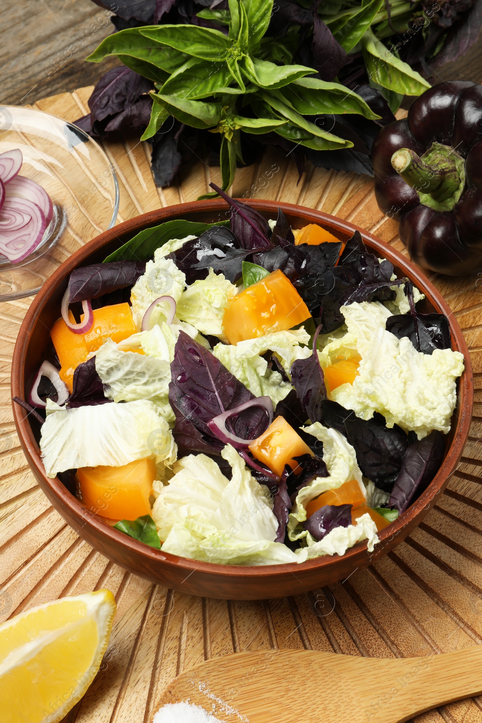 Photo of Delicious salad with Chinese cabbage, tomato and basil served on wooden table, above view