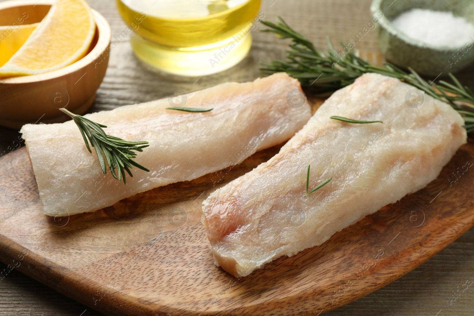 Photo of Fresh raw cod fillets, spices and lemon on wooden table, closeup