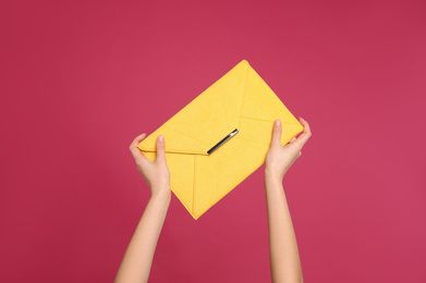 Photo of Woman holding stylish envelope bag on pink background, closeup