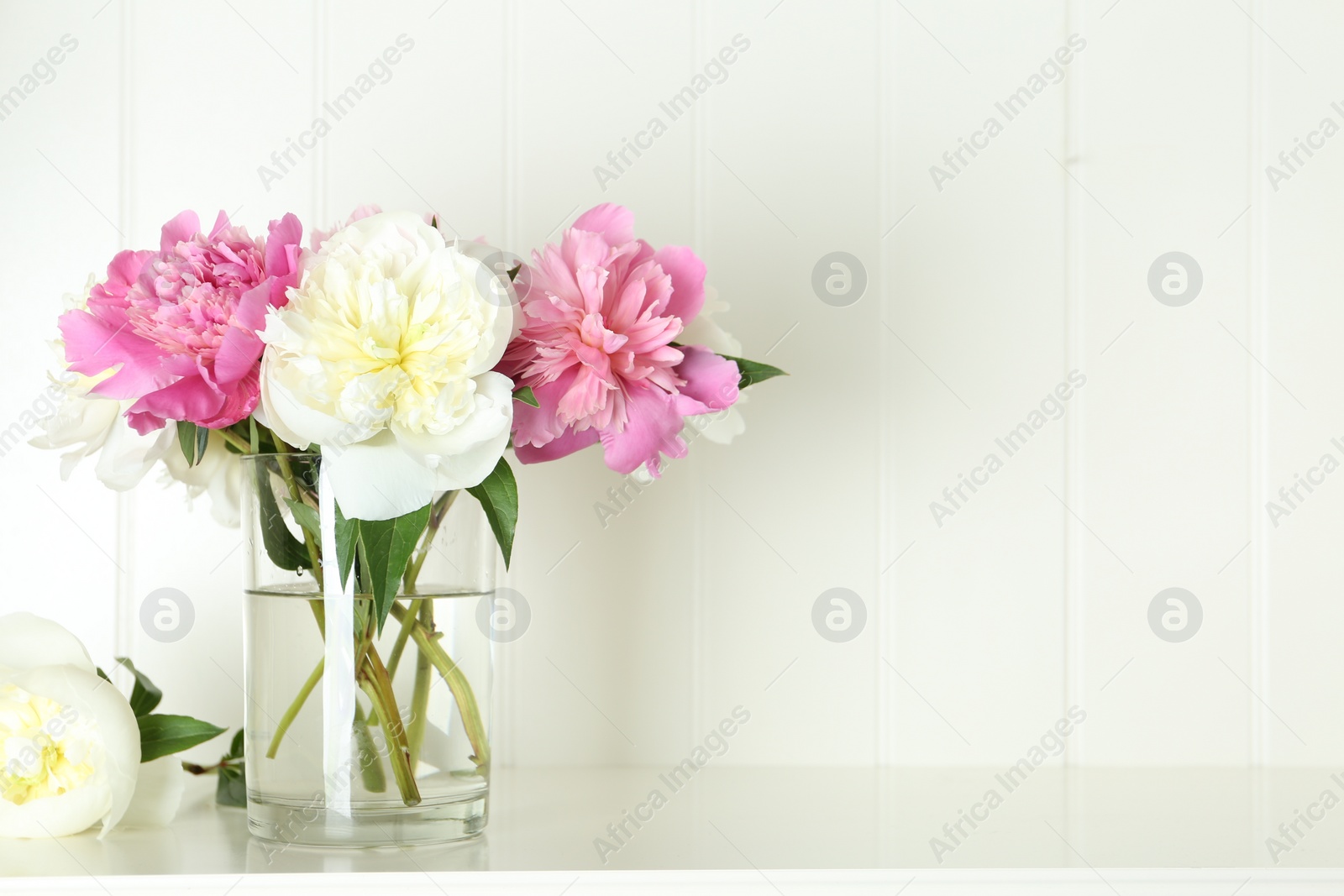 Photo of Bouquet of beautiful peonies in vase on white table. Space for text